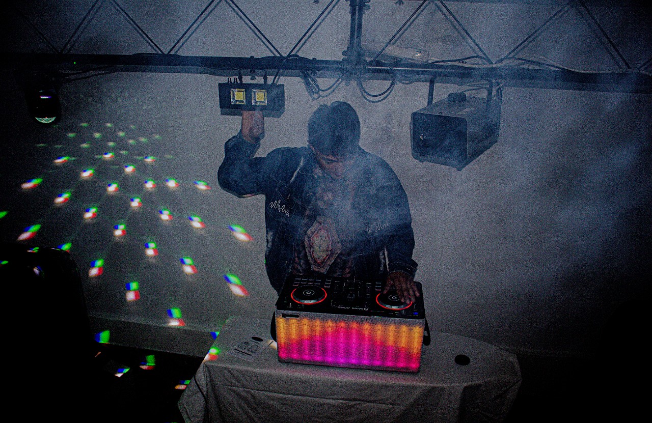 DJ en consola durante un evento con humo y luces